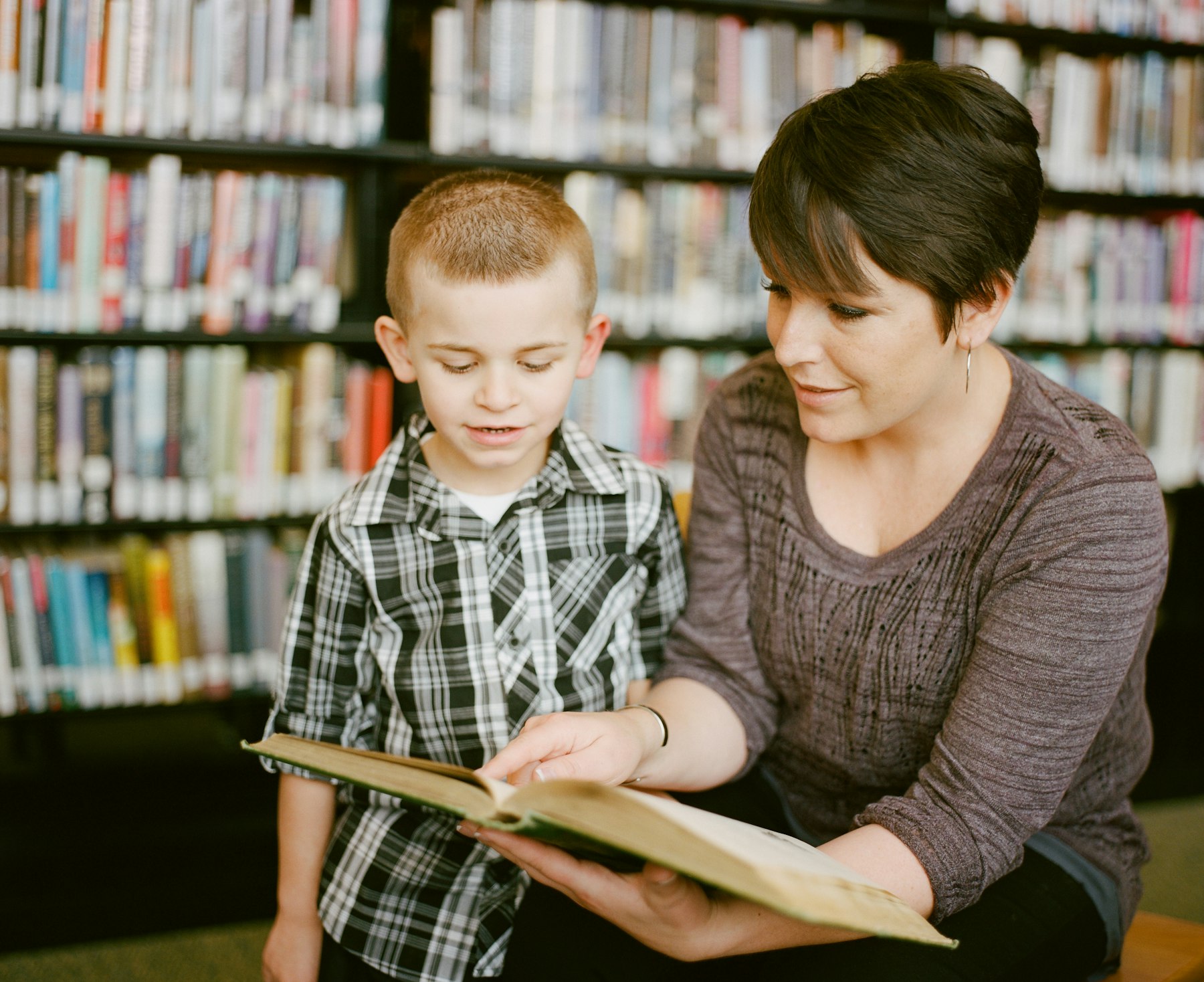 An adult and a child sitting together, reading a picture book
