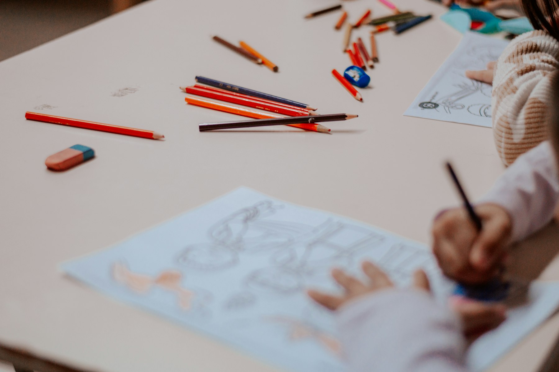 Coloured pencils scattered beside a child's drawing on a table