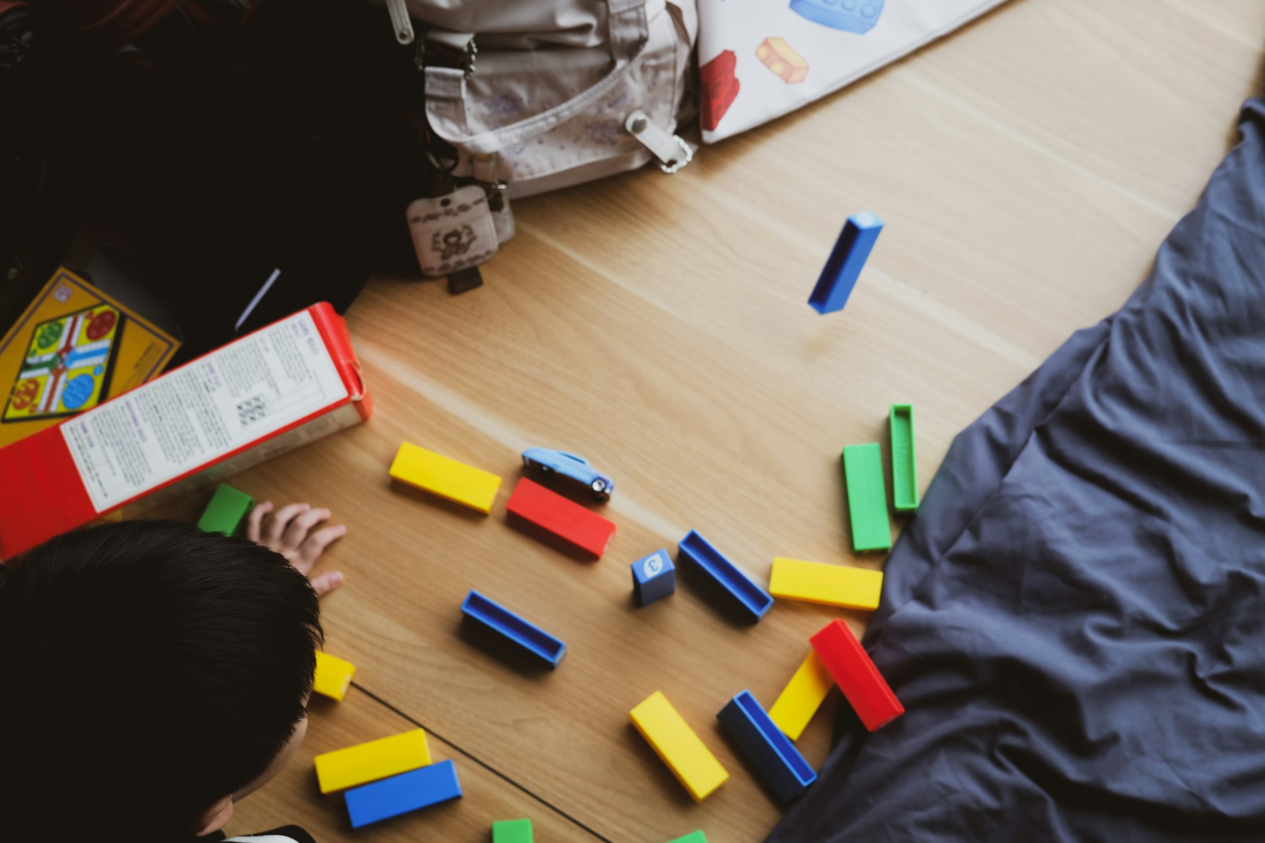 Coloured wooden blocks spread across a wooden floor during play